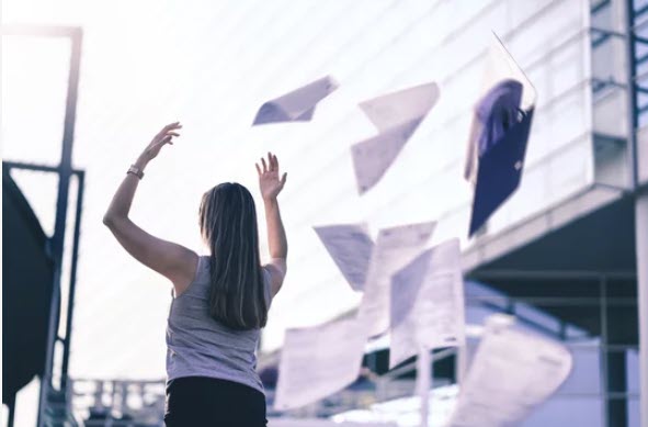 fed up girl throwing papers in the air after she quit her job