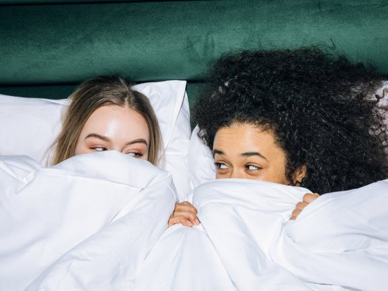 two girls having a sleepover in the same bed under the sheets