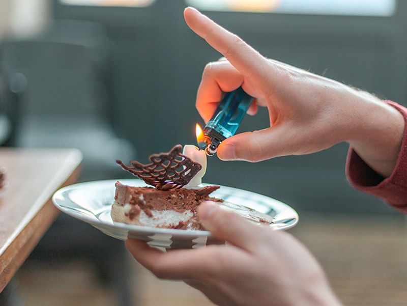 a person lighting a candle on a piece of cake