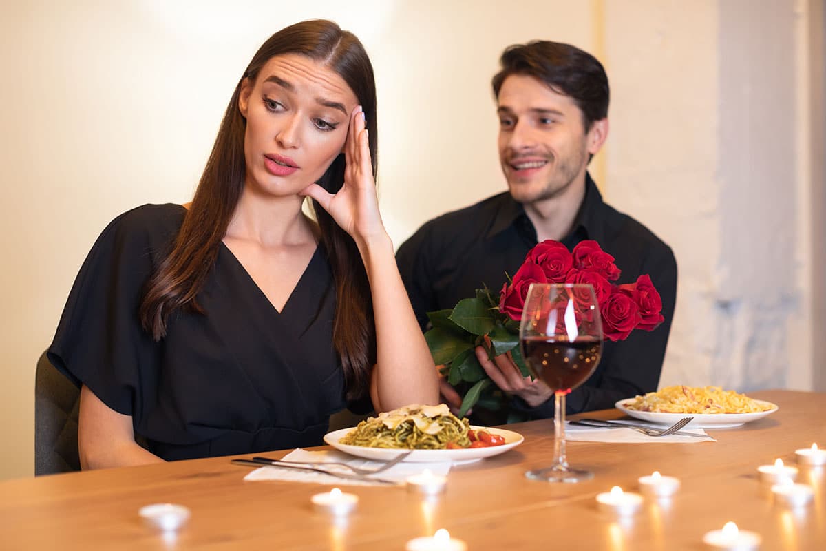 woman is trying her best to fend off a guy after a romantic dinner as she looks for excuses not to kiss after a date