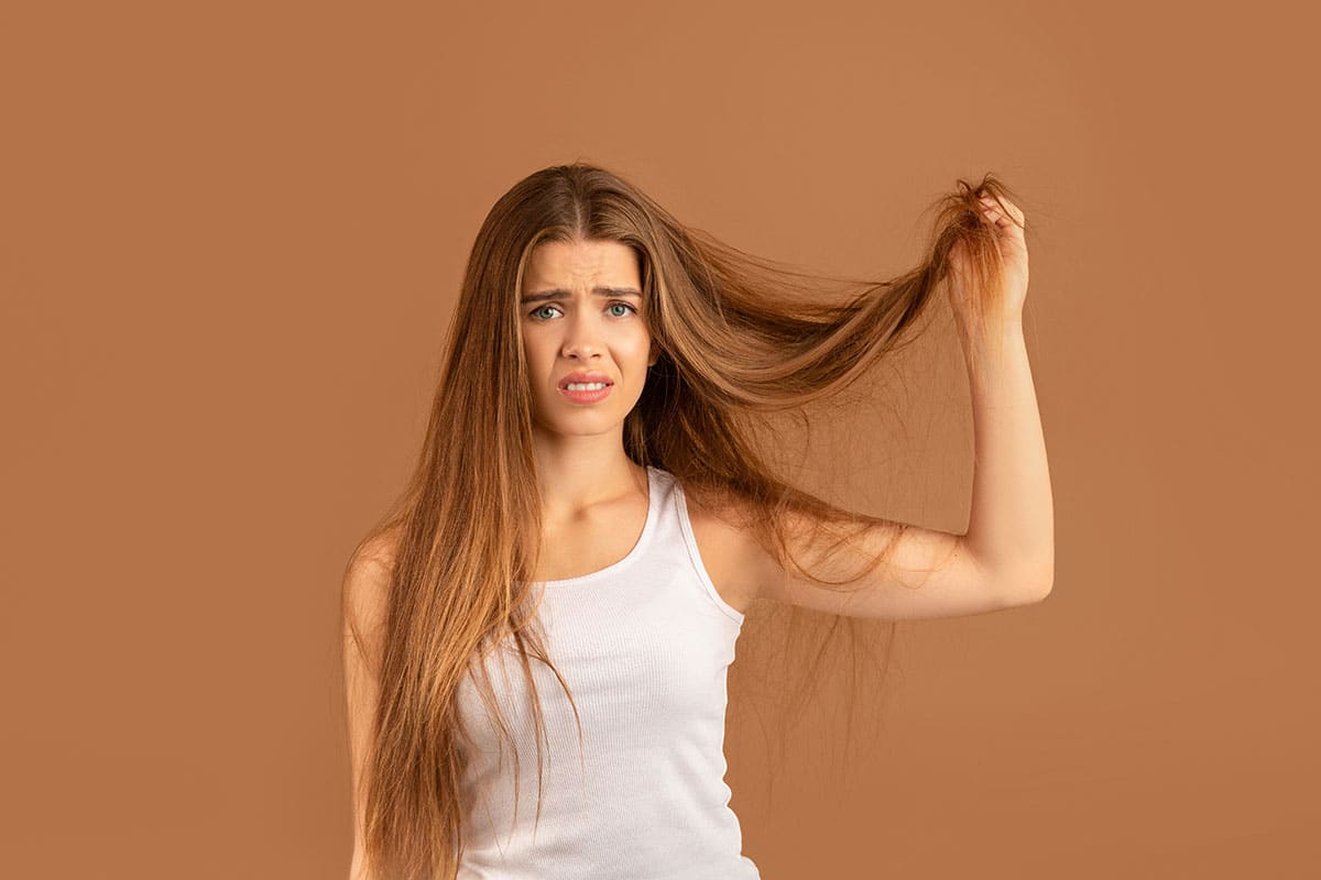 millennial woman frustrated with her frizzy unmanageable hair