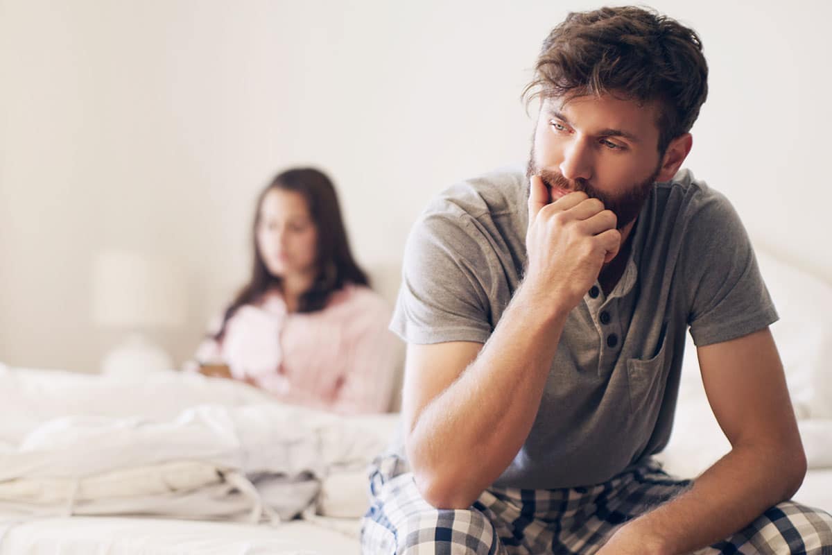 man sits on the side of a bed thinking about additional excuses for not kissing