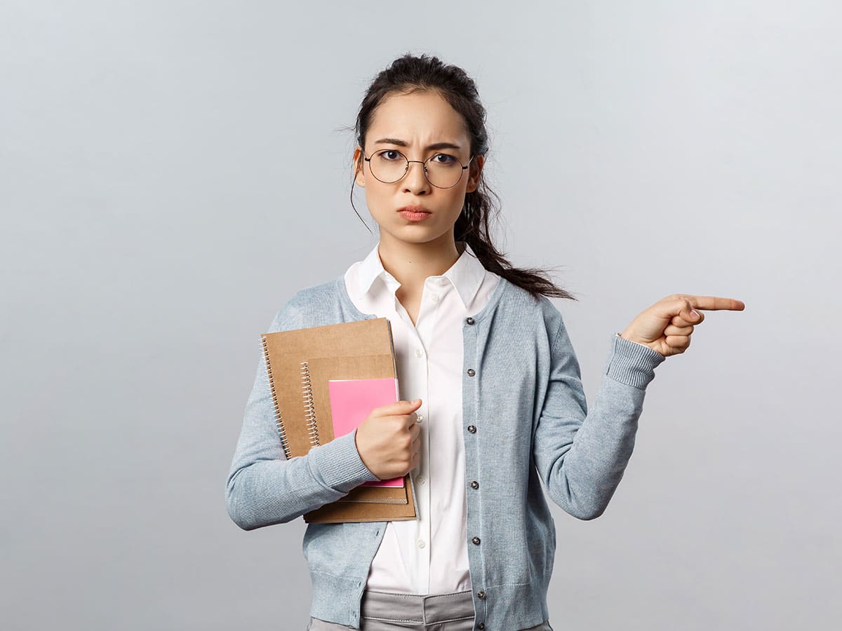 girl with glasses holding notepads, pointing to the side of her