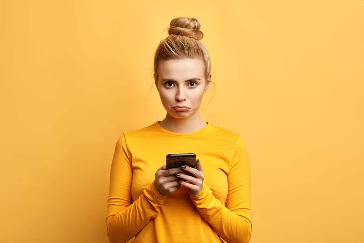 girl with upset face holding her phone while texting