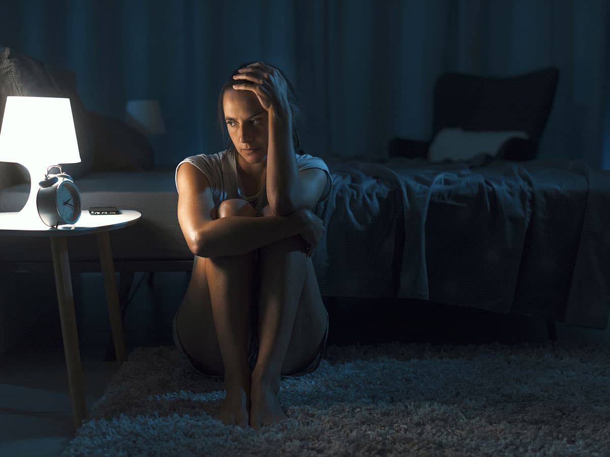 depressed woman sitting on the floor of her room in the dark contemplating excuses for cutting she can give her friends