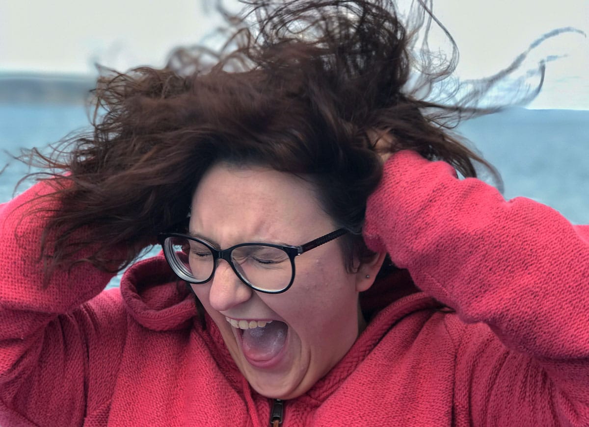 woman in red sweater and glasses pulling her hair out and screaming