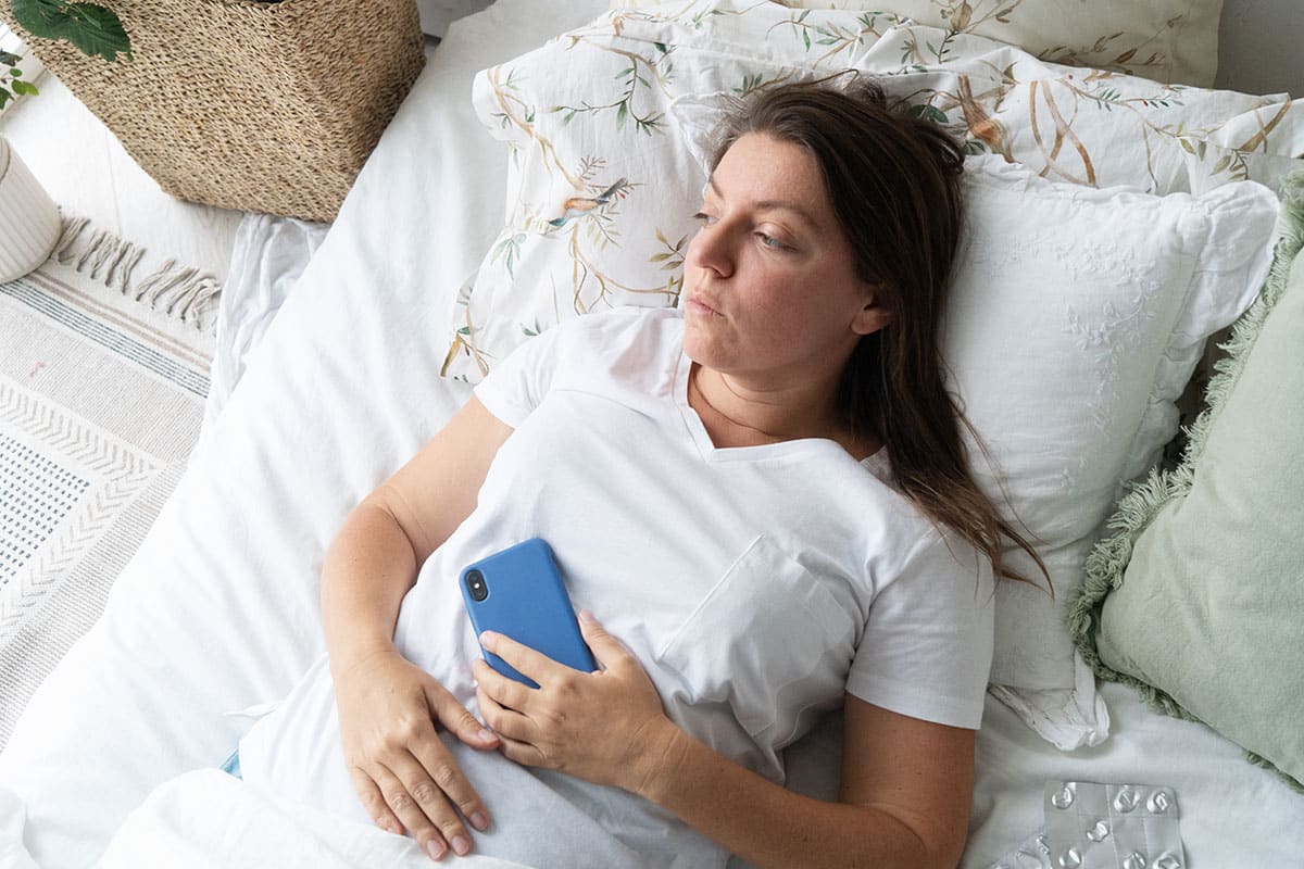 woman lies in bed with her phone because sex is too boring to have