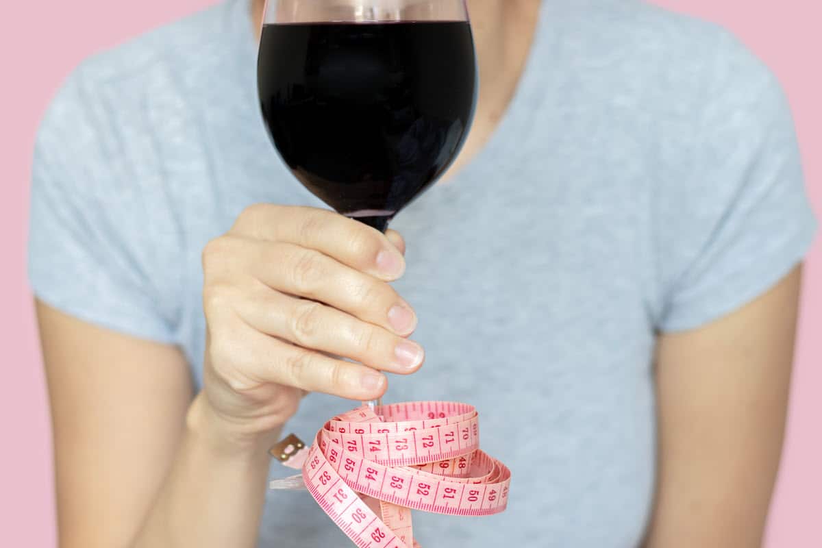 girl holding a wine glass with a tape measure wrapped around the stem