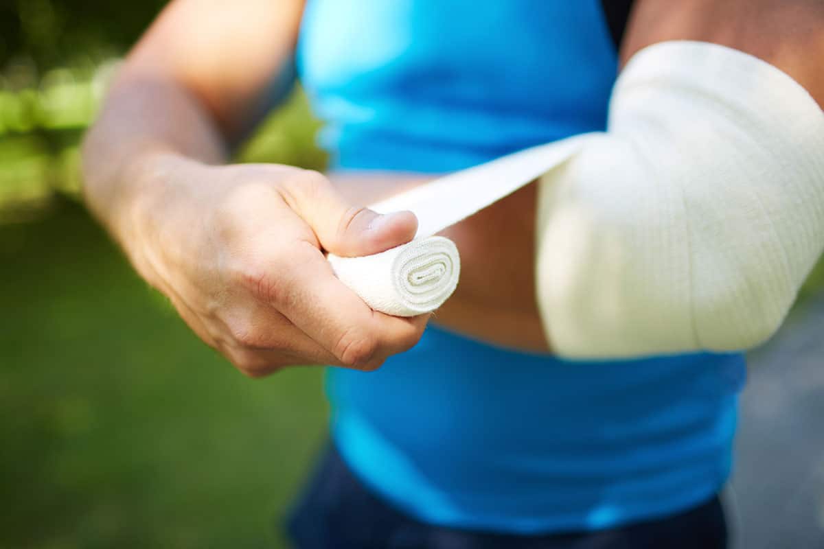 man in blue spandex wraps a bandage around his elbow