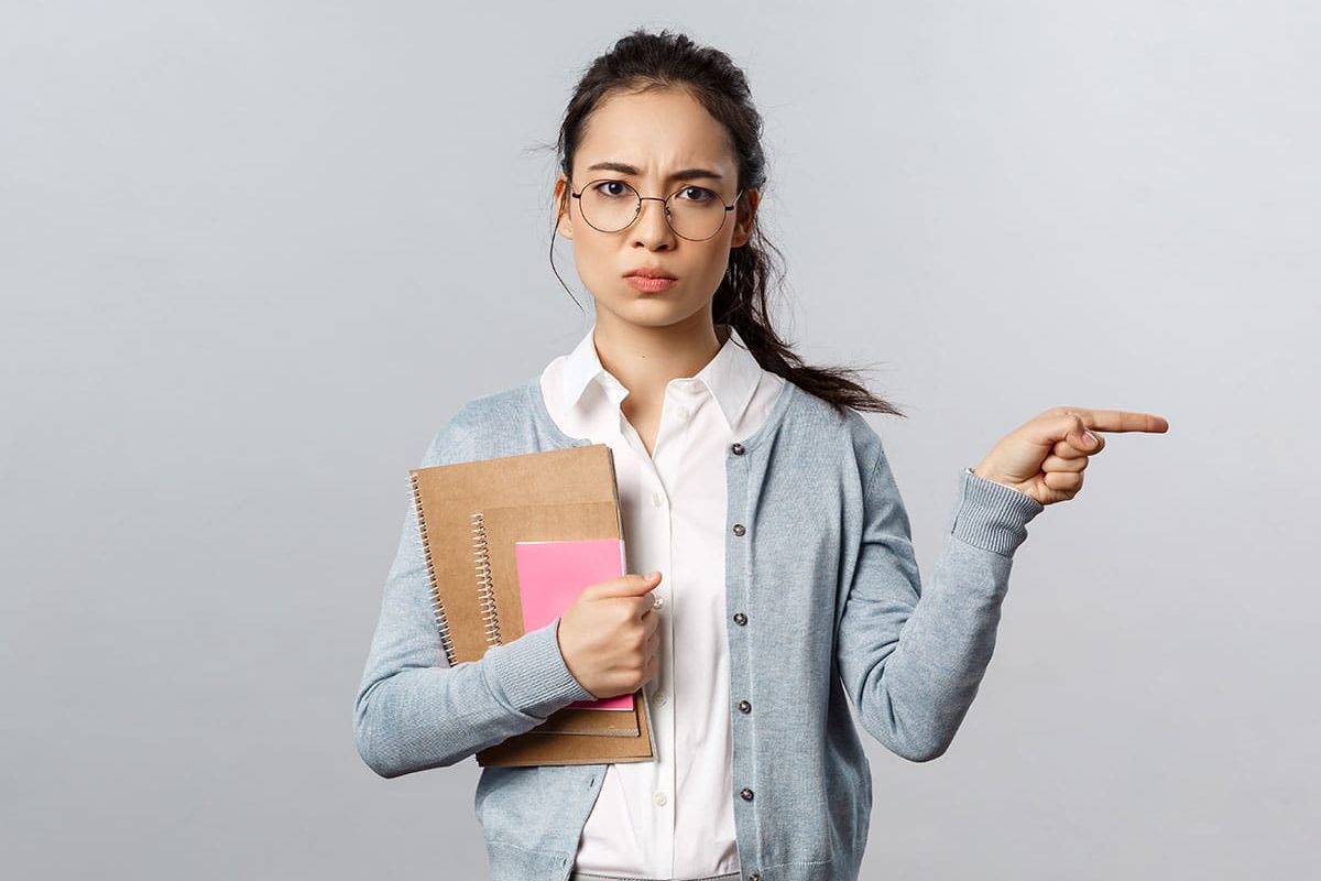 girl with glasses holding notepads, pointing to the side of her