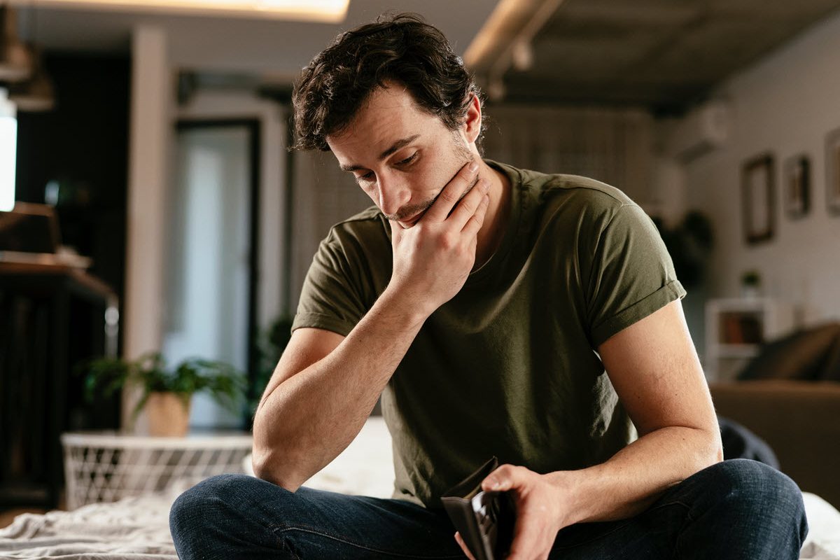 Man staring at his empty wallet