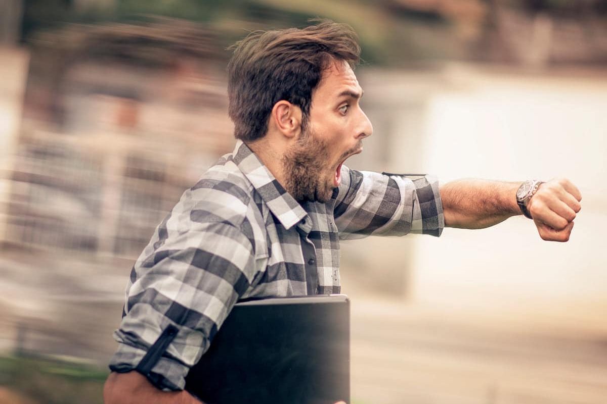 man rushing while looking at his watch because he's late to work