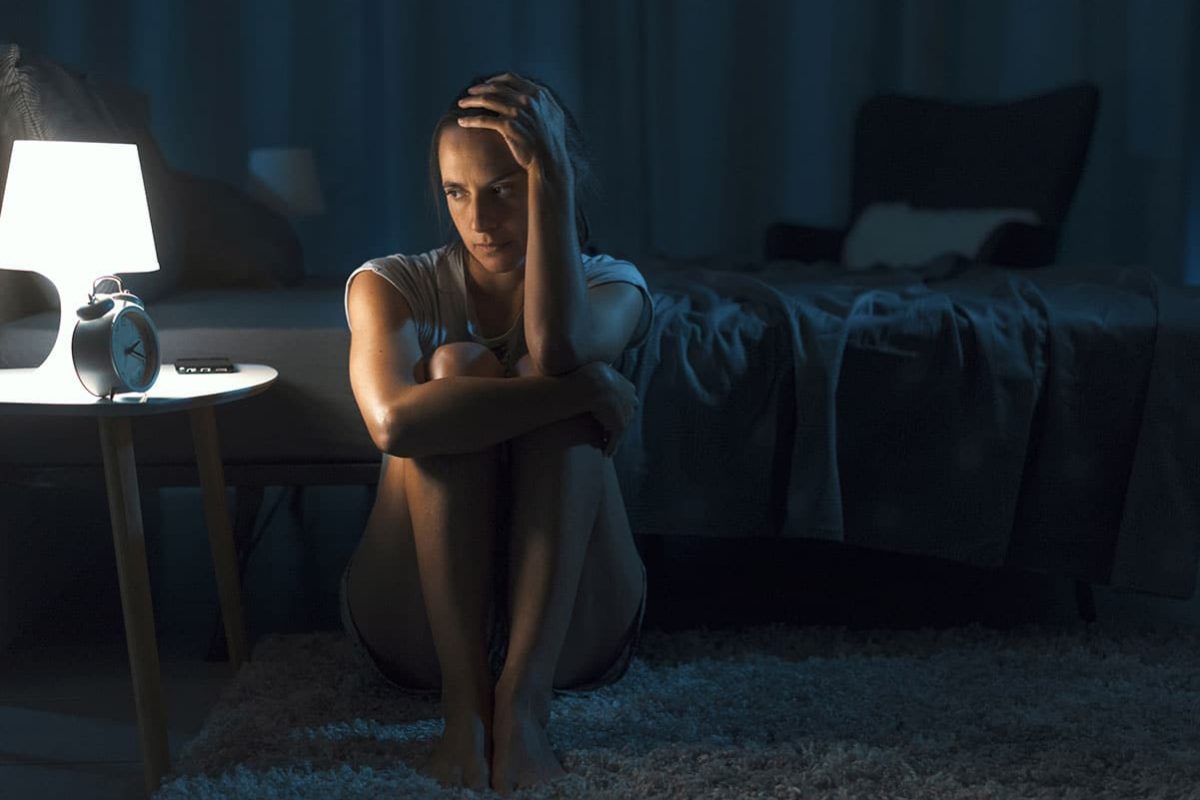 depressed woman sitting on the floor of her room in the dark contemplating excuses for cutting she can give her friends