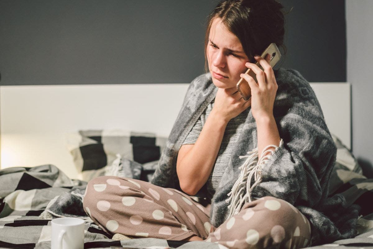 woman in bed calling in sick to work