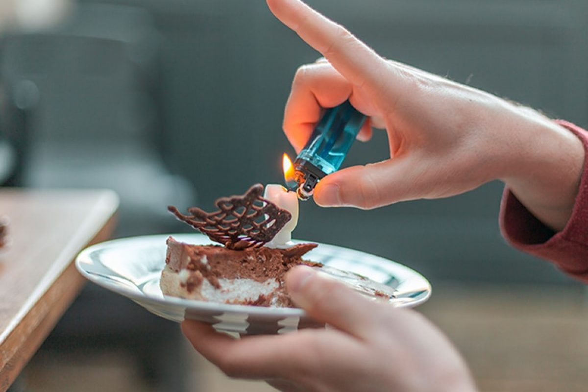 a person lighting a candle on a piece of cake