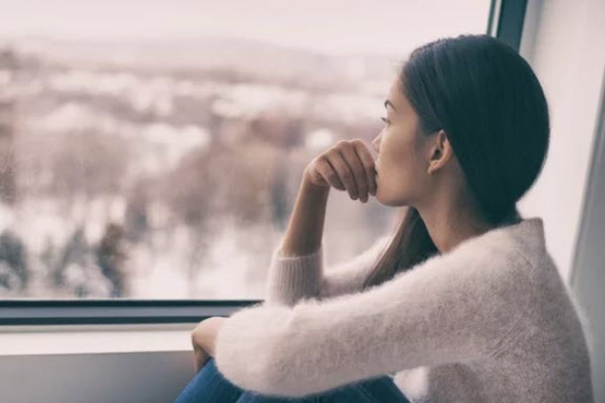 girl looking lonely staring out the window