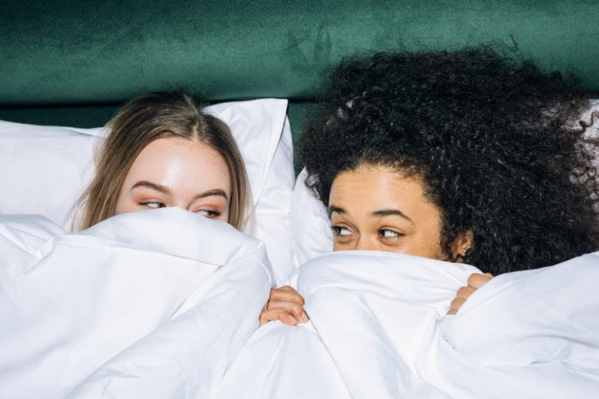 two girls having a sleepover in the same bed under the sheets